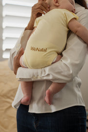 WeNatal x Tabeeze Bottom Up Bodysuit showcased on a person holding a baby, highlighting its practicality with patented Shoulder Snaps for easy changing.